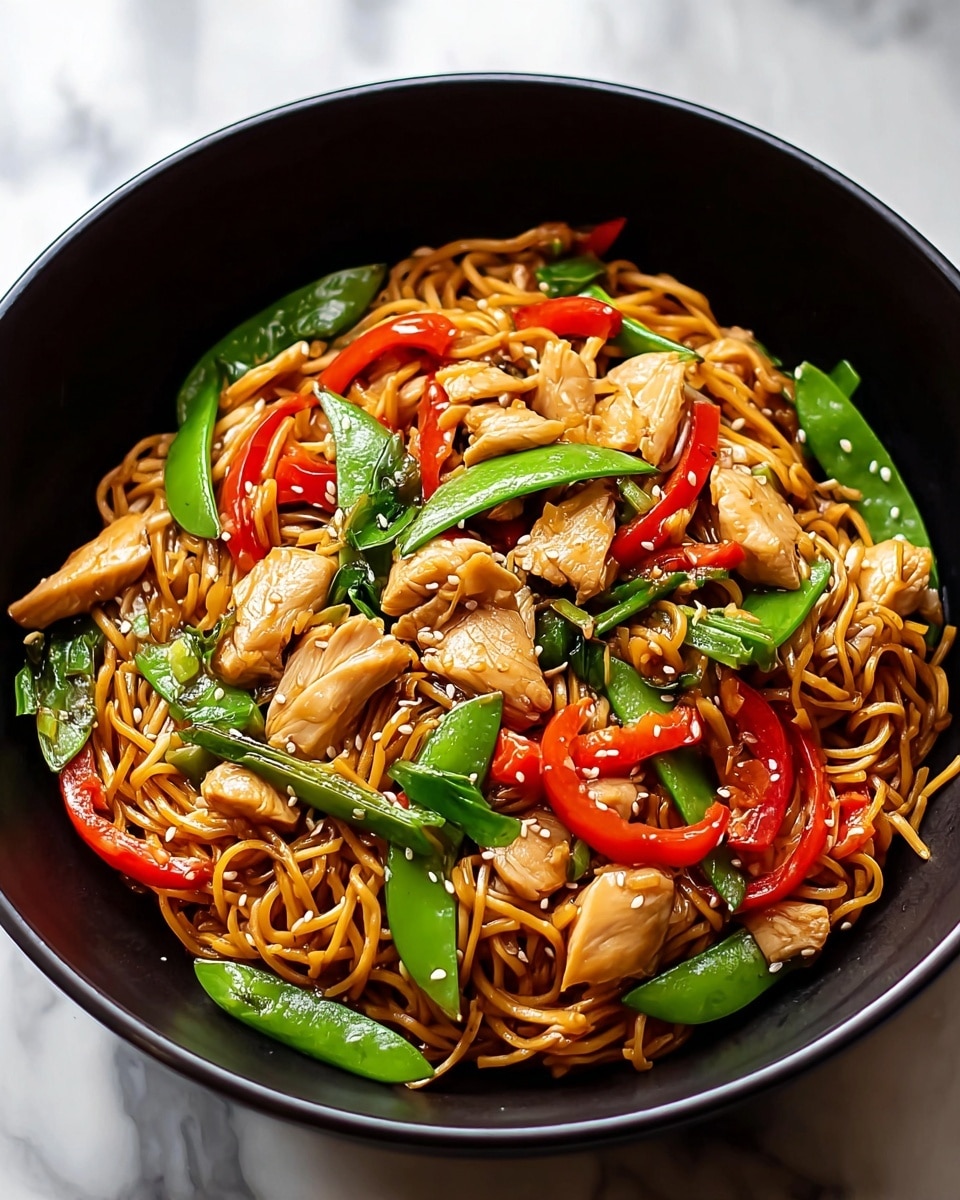 A black bowl filled with a stir-fry dish containing three main layers: the bottom layer of thin, golden-brown noodles coated lightly with sauce, the middle layer featuring chunks of light brown cooked chicken, and the top layer consisting of bright red bell pepper strips and crisp green snap peas scattered throughout, along with small white sesame seeds sprinkled over the dish. The bowl is set against a white marbled textured background. Photo taken with an iphone --ar 4:5 --v 7