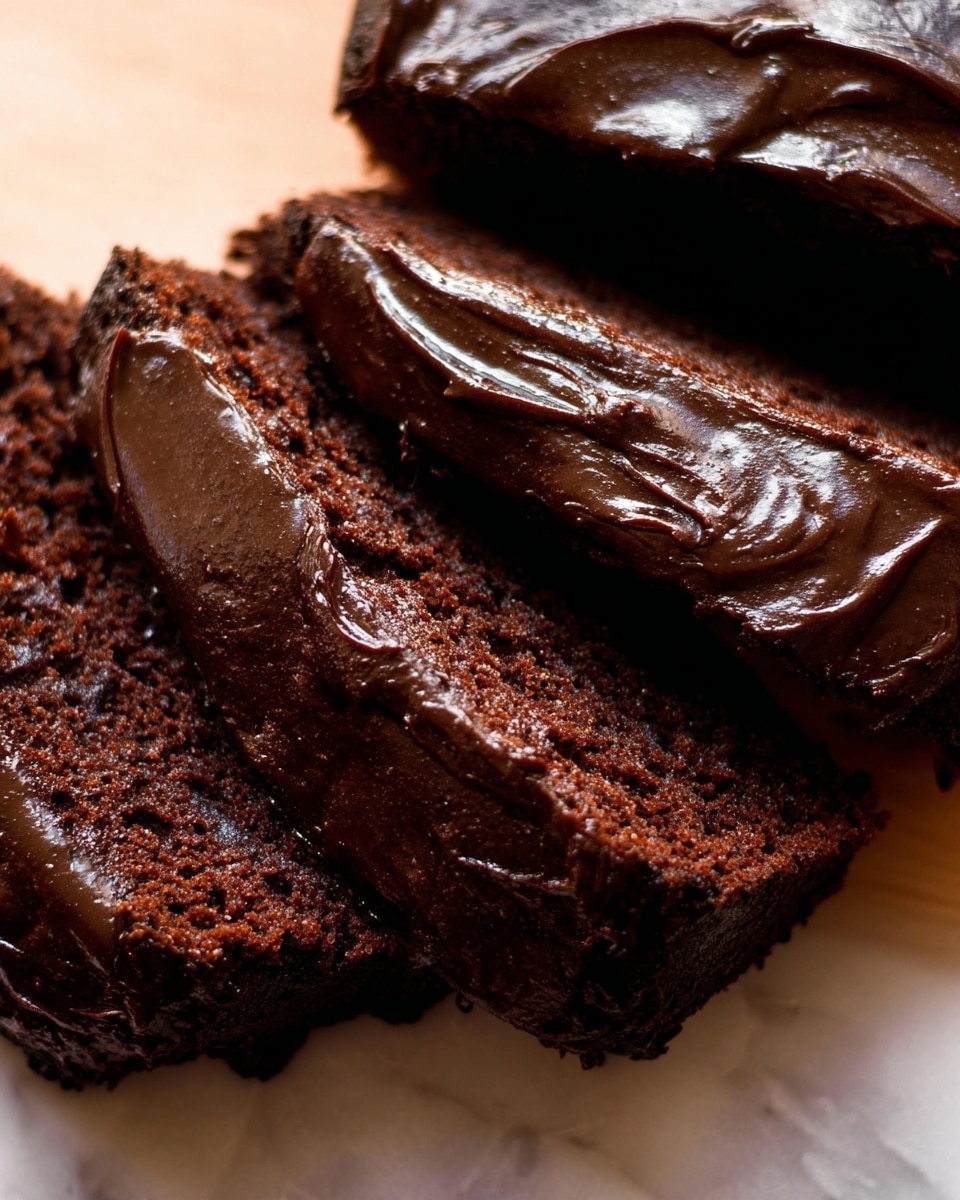 This image shows a sliced chocolate loaf cake with three visible layers on a white marbled textured surface. The top layer is a thick, shiny, smooth dark chocolate frosting with small ridges and swirls. The middle layer is a moist, dense dark chocolate cake with a slightly crumbly texture. The bottom layer is another thick, glossy layer of chocolate frosting that covers the lower part of the cake and extends slightly beyond the edges. The slices reveal the rich, dark colors and soft textures of both the cake and frosting. A knife with some frosting on it lies next to the cake, partially visible. The background includes a blurred orange pumpkin. Photo taken with an iphone --ar 4:5 --v 7