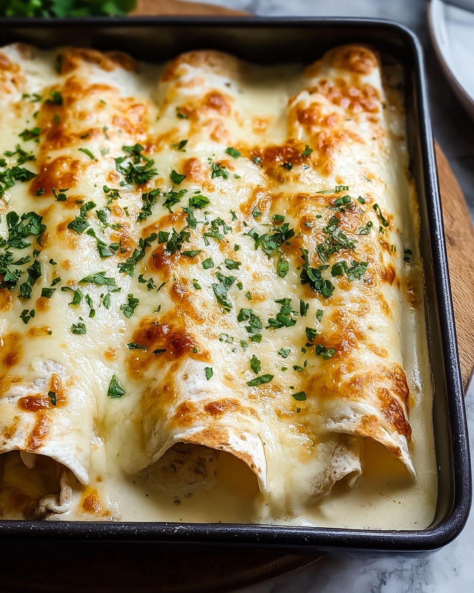 The image shows a close-up of three rolled enchiladas placed side by side in a baking tray, covered by a thick layer of melted creamy white cheese with golden brown spots from baking. The enchiladas are partially visible under the cheese, wrapped in soft, slightly browned tortillas. Fresh green chopped herbs are sprinkled evenly on top, adding a fresh color contrast. The rolled enchiladas sit in a shallow pool of creamy sauce at the bottom of the tray, which is dark and rectangular. The whole scene is set against a white marbled texture background. photo taken with an iphone --ar 4:5 --v 7